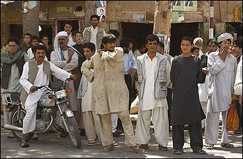 People watch as policemen carry away a bomb after it was discovered on a street in Herat, Afghanistan, Wednesday, Aug. 19, 2009. Afghans will head to the polls on Aug. 20 to elect the new president. (AP Photo/Saurabh Das)